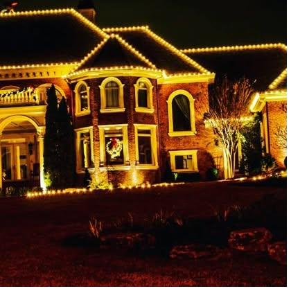 Brick estate lit warm gold, arched windows and columns picked out against a black sky