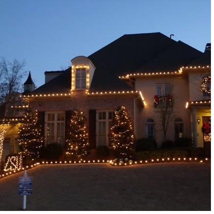 Cream estate home with driveway lighting at dusk