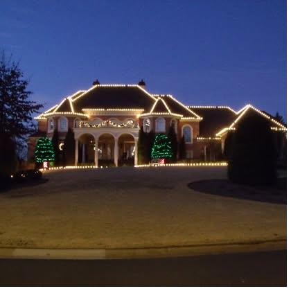 Estate home at blue dusk with twin trees wrapped in lights