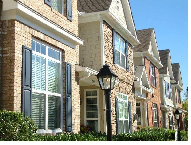 Row of brick and stone townhomes with repainted trim, shutters and cornices